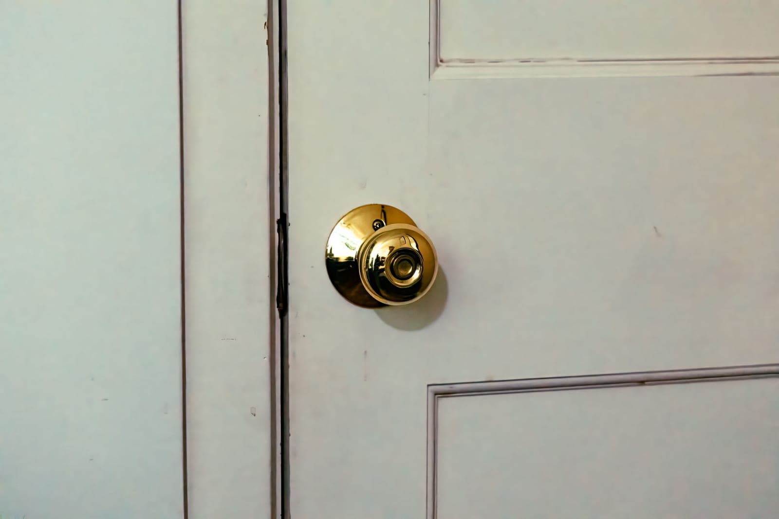 A classic white paneled front door with a polished brass handle and deadbolt